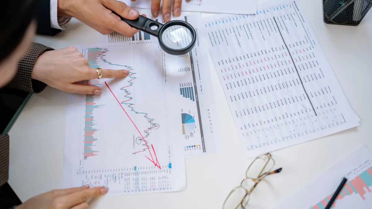 hands reviewing charts with a magnifying glass