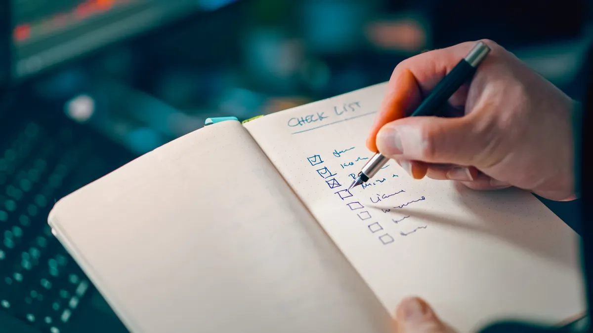 Hand ticking off items on a checklist notebook