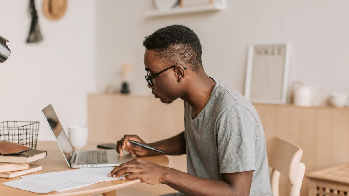 student studying and writing beside a laptop