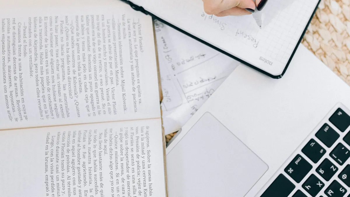 Jasper AI review for bloggers — Woman Writing Down in Planner near Open Book and Laptop